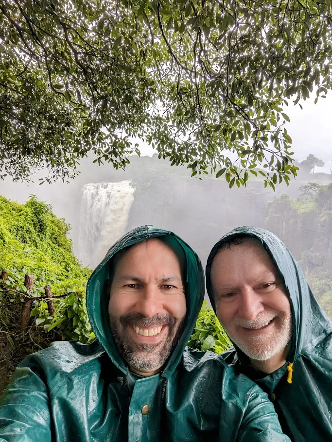 James and Rob exploring in raincoats beside a waterfall
